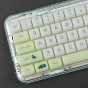 Jade Canopy pale green translucent MAO keycaps with botanical animal motifs, keyboard close-up on a charcoal surface. Keyboard is not included.