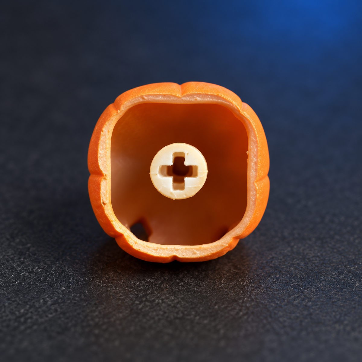 Underside of Pumpkin Glow resin keycap, showing the recessed cross-shaped mounting socket.