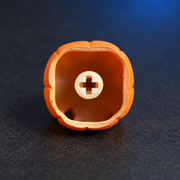 Underside of Pumpkin Glow resin keycap, showing the recessed cross-shaped mounting socket.