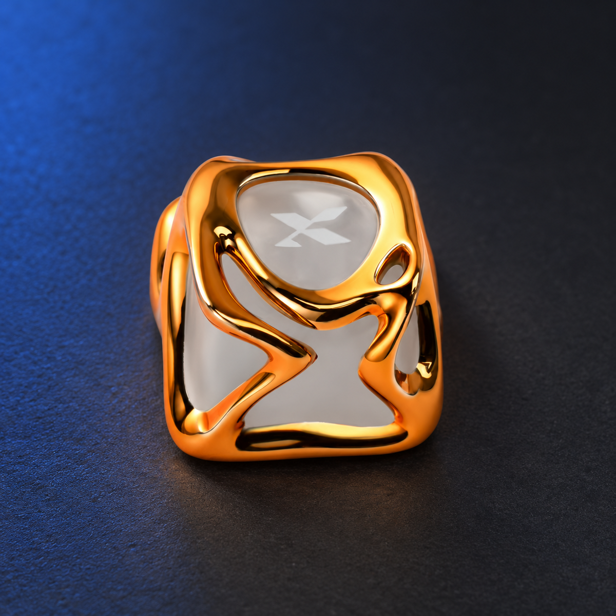Molten Gold sculpted gold-colour XVX accent keycap, angled studio view on charcoal with soft blue background lighting.
